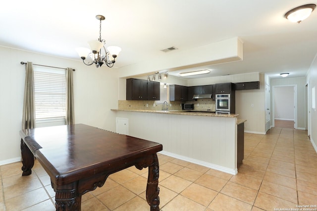 kitchen featuring visible vents, decorative backsplash, appliances with stainless steel finishes, a peninsula, and under cabinet range hood