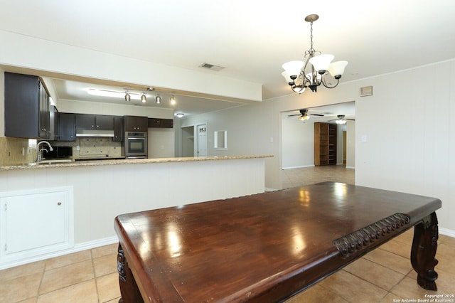 kitchen featuring tasteful backsplash, visible vents, stainless steel oven, a peninsula, and ceiling fan with notable chandelier