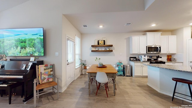 kitchen with light stone countertops, stainless steel appliances, visible vents, white cabinets, and decorative backsplash