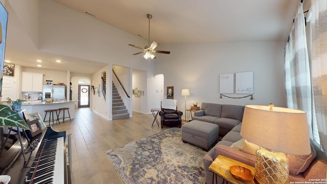 living area featuring recessed lighting, ceiling fan, high vaulted ceiling, light wood-type flooring, and stairs