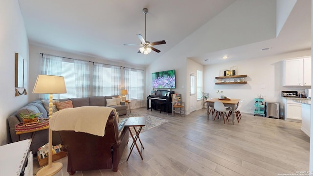 living area featuring light wood finished floors, visible vents, baseboards, ceiling fan, and high vaulted ceiling