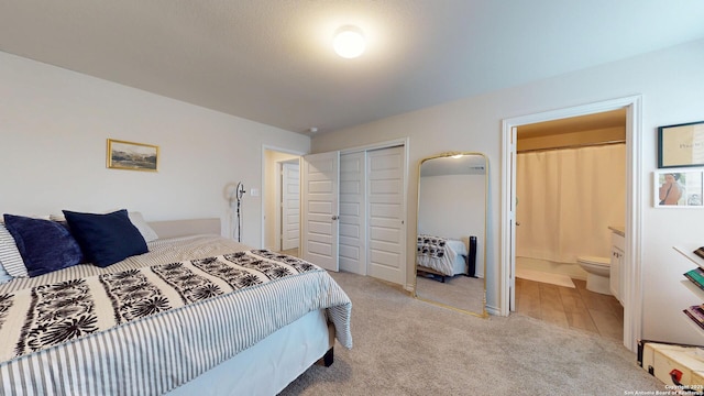 bedroom with a closet, light colored carpet, and connected bathroom