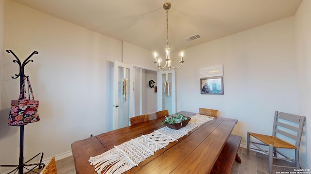 dining room featuring a chandelier, wood finished floors, visible vents, and baseboards