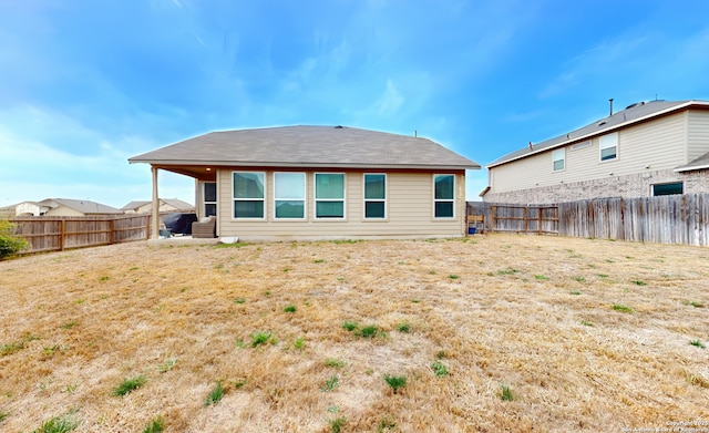 rear view of house featuring a fenced backyard and a lawn