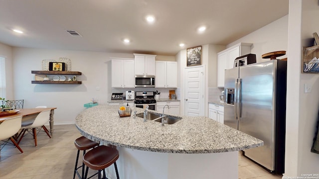 kitchen featuring stainless steel appliances, white cabinets, a sink, and tasteful backsplash