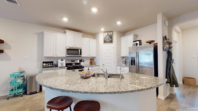 kitchen featuring visible vents, decorative backsplash, stainless steel appliances, white cabinetry, and a sink