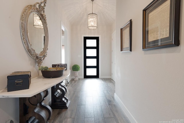 entryway with a chandelier, wood finished floors, and baseboards