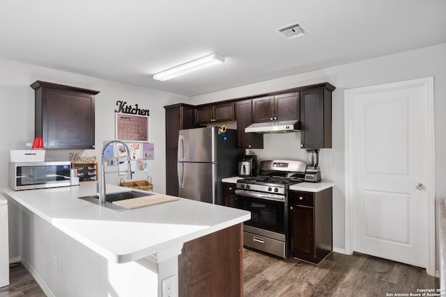 kitchen with stainless steel appliances, a sink, dark brown cabinetry, and under cabinet range hood