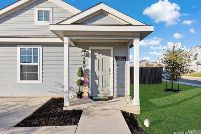 entrance to property featuring a lawn and fence