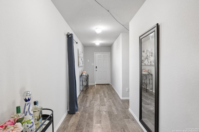 corridor featuring baseboards and wood finished floors