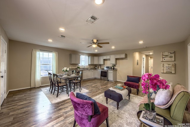 living room featuring baseboards, visible vents, wood finished floors, and recessed lighting