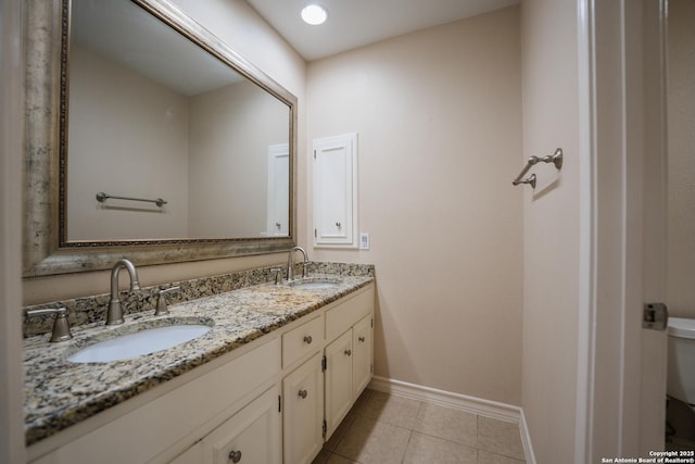 bathroom featuring tile patterned flooring, a sink, baseboards, and double vanity