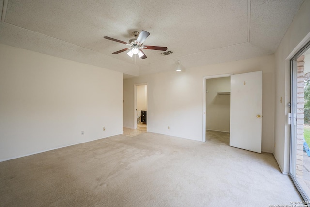 spare room featuring light carpet, a textured ceiling, visible vents, and a ceiling fan