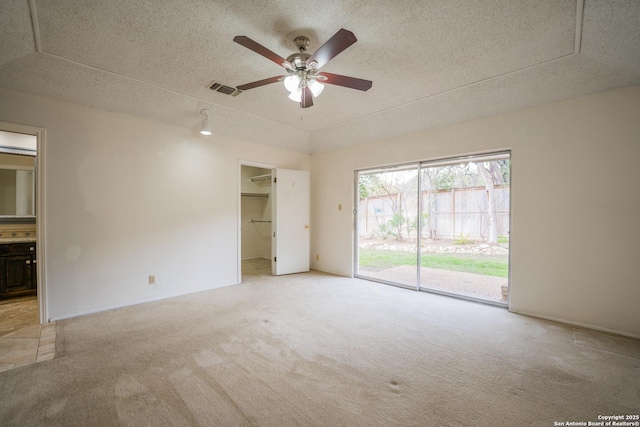 spare room featuring a ceiling fan, visible vents, light carpet, and a textured ceiling