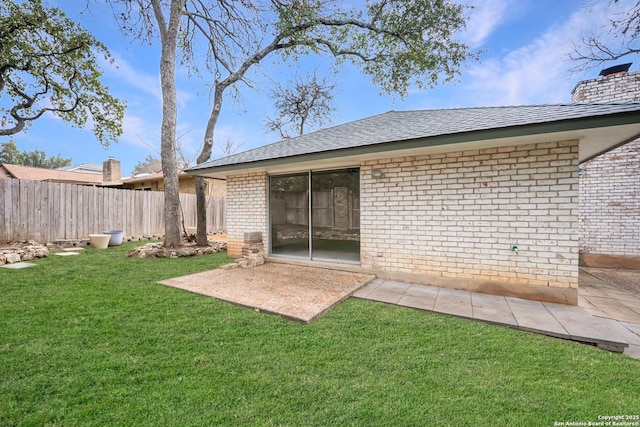 rear view of house with a lawn, a chimney, fence, a patio area, and brick siding