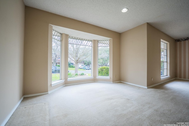 carpeted spare room featuring baseboards, a textured ceiling, and recessed lighting