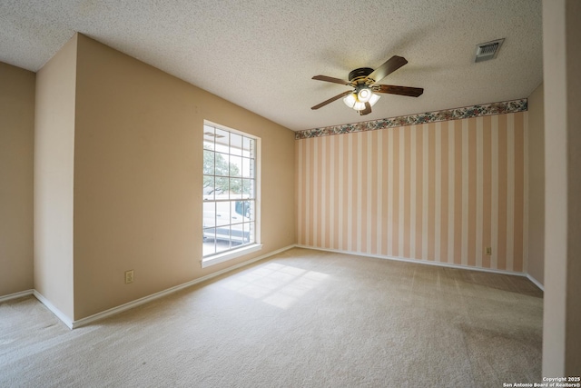 carpeted spare room with visible vents, baseboards, ceiling fan, and a textured ceiling