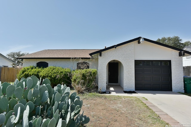 view of front of property featuring driveway, brick siding, an attached garage, and fence