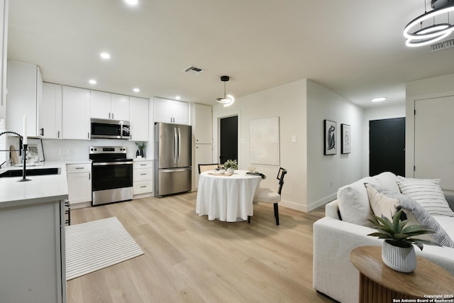 kitchen with stainless steel appliances, light countertops, visible vents, and a sink