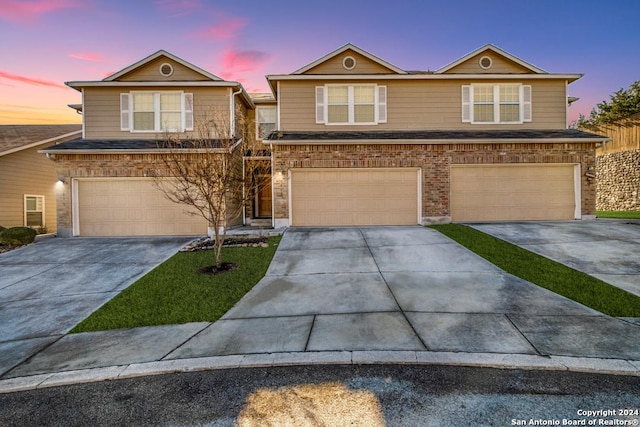 traditional-style home featuring a garage, concrete driveway, and brick siding