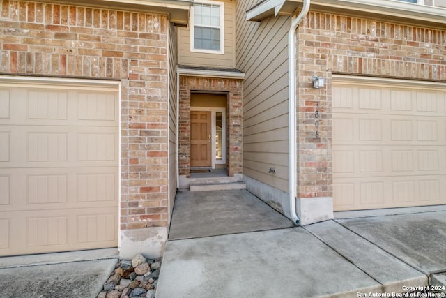 property entrance featuring a garage and brick siding