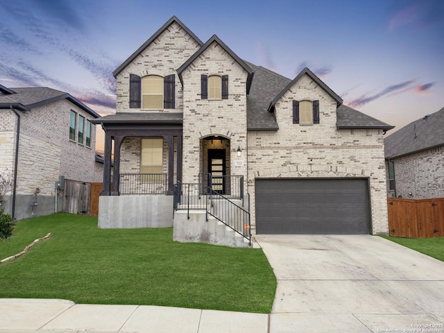 french provincial home featuring a garage, brick siding, and a front yard