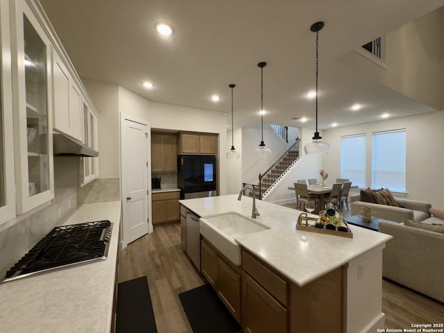 kitchen with decorative backsplash, appliances with stainless steel finishes, wood finished floors, light countertops, and a sink