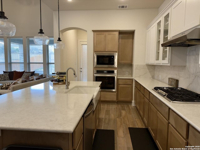 kitchen with arched walkways, visible vents, backsplash, appliances with stainless steel finishes, and a sink