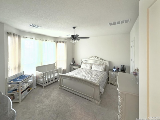 bedroom featuring a textured ceiling, ceiling fan, carpet, and visible vents