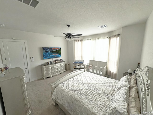 carpeted bedroom featuring a ceiling fan, visible vents, and a textured ceiling