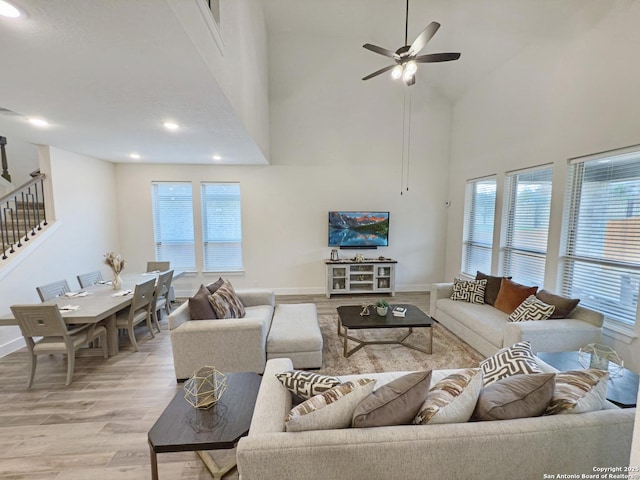 living area with light wood-type flooring, a healthy amount of sunlight, stairs, and baseboards