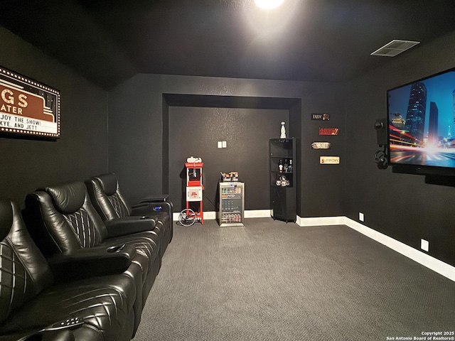 carpeted cinema room featuring visible vents and baseboards