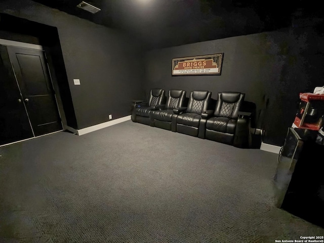 carpeted cinema room featuring lofted ceiling and baseboards