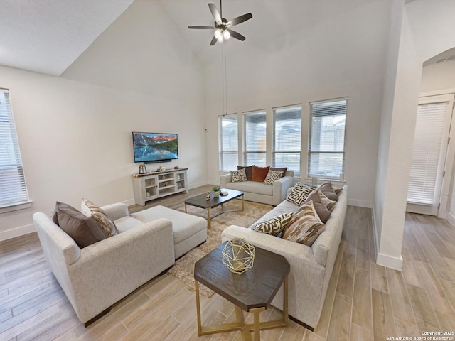 living area with light wood-style floors, baseboards, high vaulted ceiling, and a ceiling fan