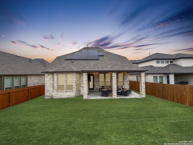 back of property at dusk with a yard, a fenced backyard, a patio, and a shingled roof