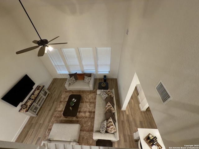 living area with visible vents, ceiling fan, baseboards, and wood finished floors