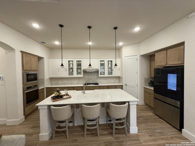 kitchen featuring built in microwave, stainless steel oven, a breakfast bar area, and wood finish floors