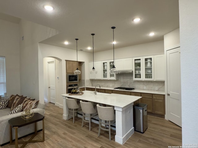 kitchen featuring arched walkways, stainless steel appliances, a sink, and wood finished floors