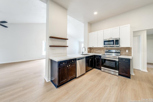 kitchen featuring white cabinets, decorative backsplash, stainless steel appliances, and light countertops