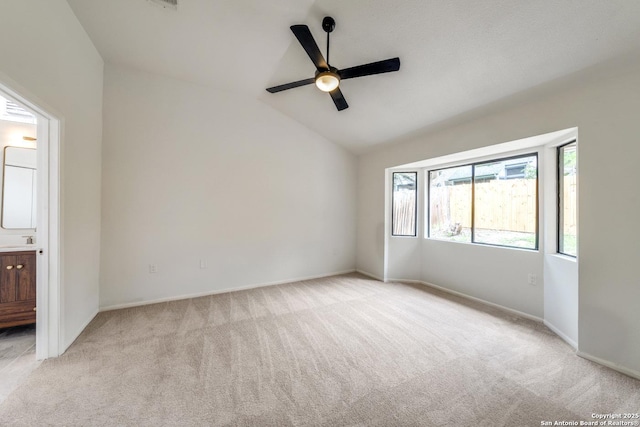 spare room with vaulted ceiling, a sink, a ceiling fan, and light colored carpet