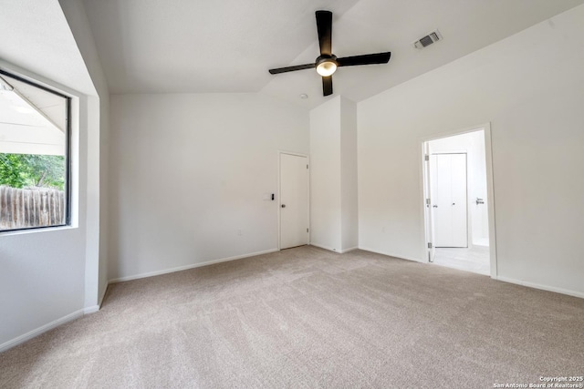 carpeted empty room featuring lofted ceiling, ceiling fan, visible vents, and baseboards