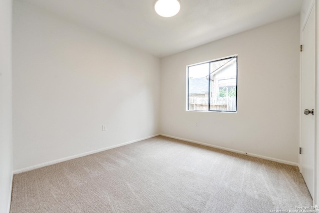 unfurnished room with light carpet and baseboards