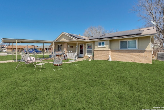 view of front of house featuring brick siding, a front lawn, and solar panels