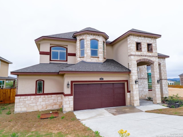 french country inspired facade featuring an attached garage, a shingled roof, concrete driveway, and stucco siding