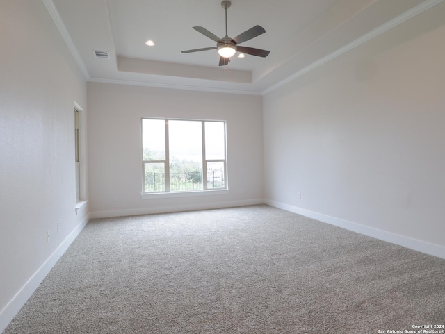 empty room featuring ceiling fan, visible vents, baseboards, a tray ceiling, and carpet