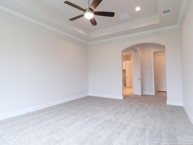 spare room featuring arched walkways, light colored carpet, visible vents, baseboards, and a raised ceiling