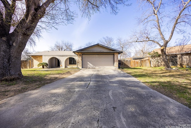 view of front of home featuring concrete driveway, brick siding, an attached garage, and fence