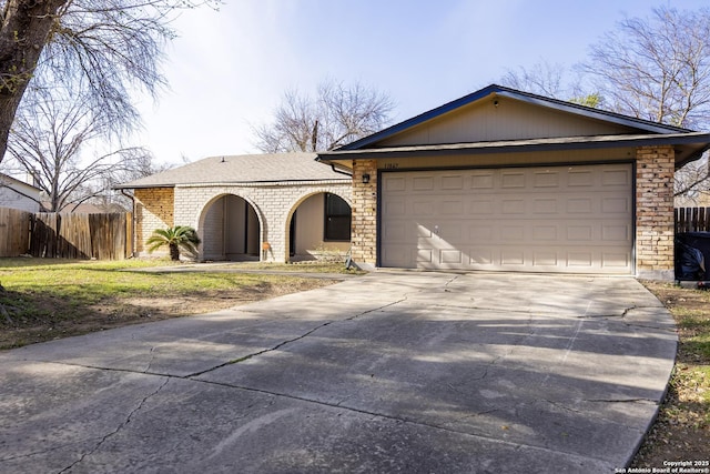 view of front of house featuring brick siding, driveway, an attached garage, and fence