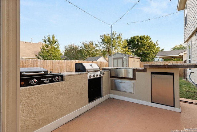 view of patio / terrace featuring an outbuilding, a fenced backyard, a sink, and a storage unit