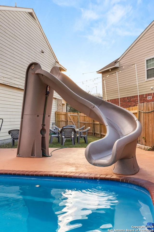 view of swimming pool featuring a water slide, fence, and a fenced in pool